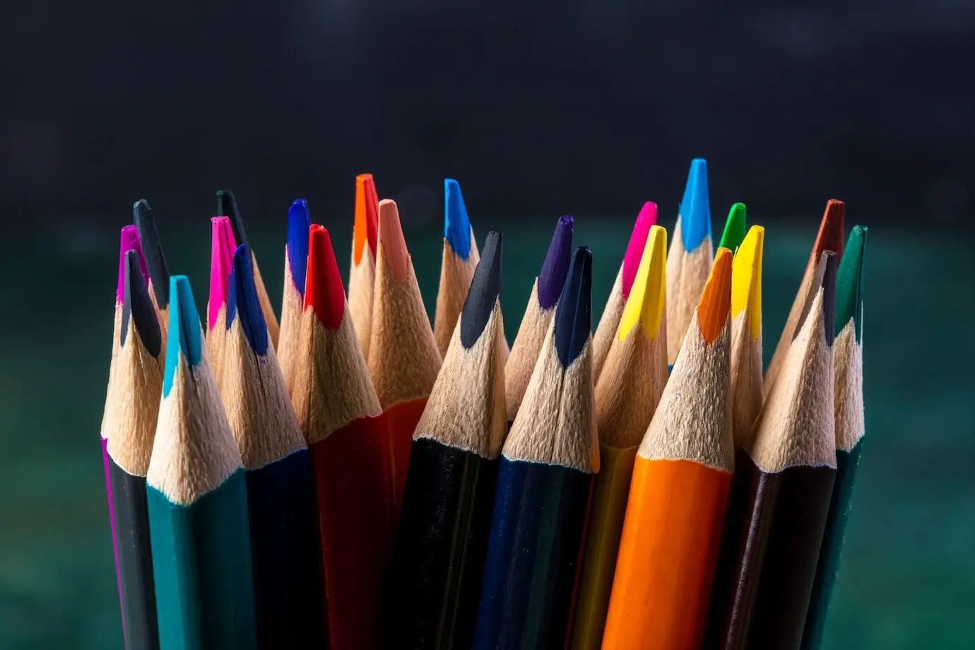 Seitenansicht eines Bündels von Buntstiften auf Dunklem.